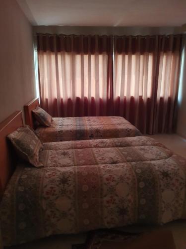 1 Schlafzimmer mit 2 Betten und einem Fenster mit Vorhängen in der Unterkunft Appartement confortable - Sfax centre in Sfax