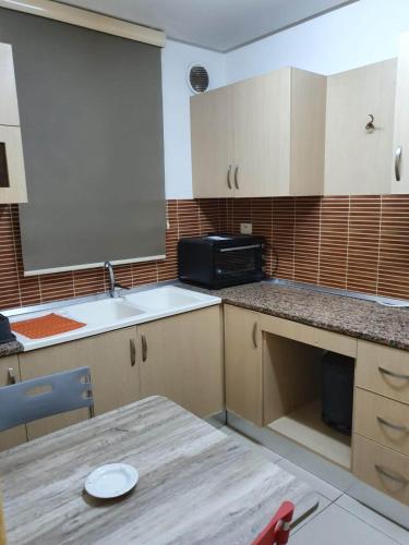 eine kleine Küche mit einem Tisch und einer Mikrowelle in der Unterkunft Appartement confortable - Sfax centre in Sfax