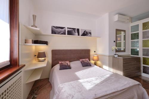 ガルダにあるApartmentsGarda - GardaLux Apartmentsのベッドルーム1室(ベッド1台、ランプ2つ、窓付)
