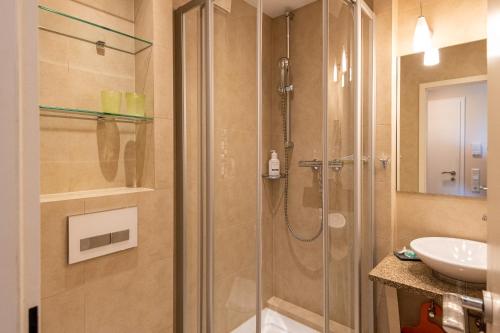 La salle de bains est pourvue d'une douche et d'un lavabo. dans l'établissement Syltdomizil Westsuite, à Wenningstedt