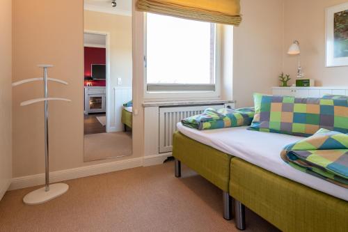 Schlafzimmer mit einem Bett, einem Fenster und einem Spiegel in der Unterkunft Syltdomizil Westsuite in Wenningstedt-Braderup