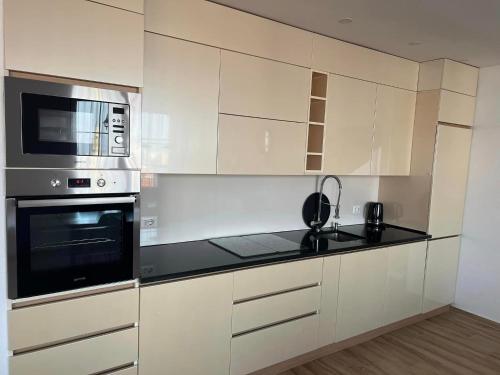 a kitchen with white cabinets and a microwave at Kalaja Apartment in Prizren