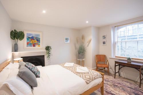 1 dormitorio con cama, escritorio y chimenea en Spacious 1BR Victorian Cheltenham flat in Cotswolds Sleeps 4 - FREE Parking, en Cheltenham