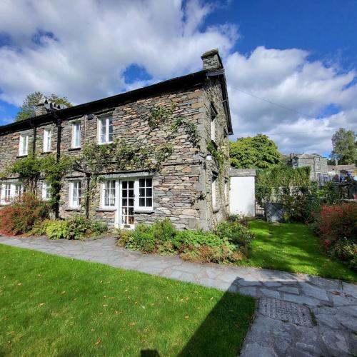 an old stone house with a green yard at 1 Bridge Syke Elterwater in Ambleside