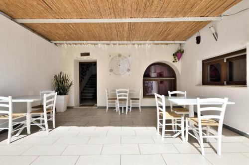d'une terrasse avec des tables et des chaises blanches et un plafond en bois. dans l'établissement Al Vicoletto - Genuine Hospitality, à Tortolì