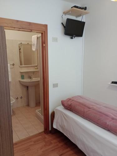 a room with a bed and a bathroom with a sink at Sasso Nero in Chiesa in Valmalenco