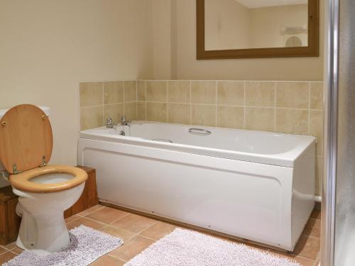 a bathroom with a white tub and a toilet at Dairy Cottage - Ukc3735 in Bawdeswell
