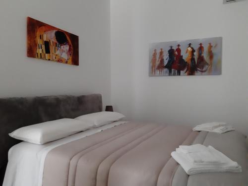 - un lit avec des draps blancs et une photo sur le mur dans l'établissement Casa Lucia, à Bari