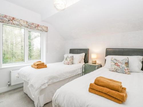 two beds in a room with white walls and a window at Orchard House in Leominster