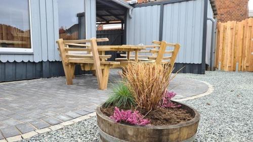 a patio with a wooden table and bench and flowers at Ferienhaus-Abendsonne-Familie-Sikora in Fehmarn