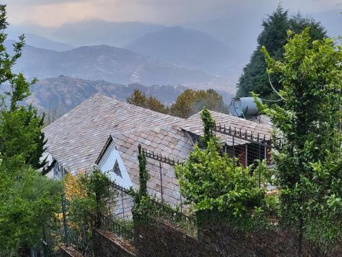 a roof of a house with trees and mountains in the background at NALDUM VILLAGE RESORT By The Edge Nagarkot in Nagarkot