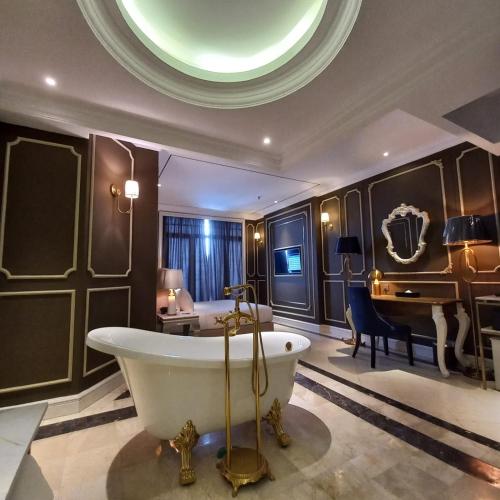 a bathroom with a tub and a bed and a piano at Grand Eska Hotel & Suites Batam in Nagoya