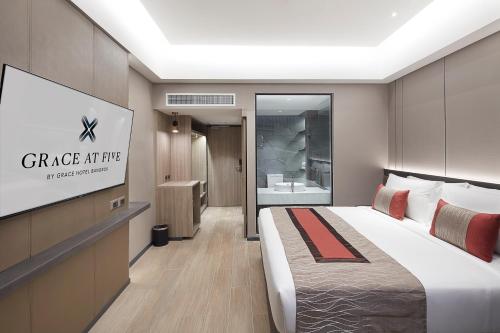 a hotel room with a bed and a projection screen at Grace At Five by Grace Hotel Bangkok in Bangkok