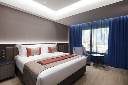 a hotel room with a bed and a desk and a window at Grace At Five by Grace Hotel Bangkok in Bangkok
