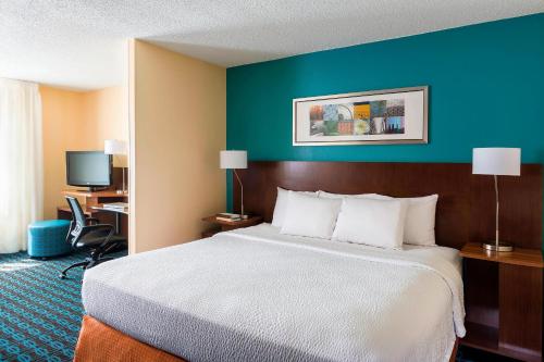a hotel room with a bed and a blue wall at Fairfield Inn & Suites Dallas Park Central in Dallas