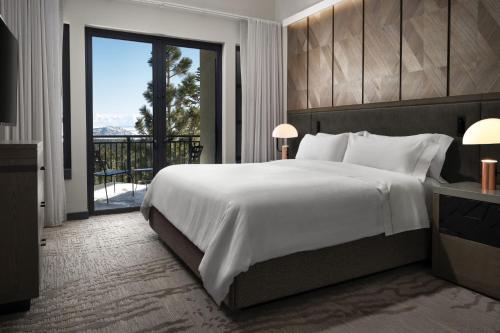 a bedroom with a large white bed and a balcony at The Westin Monache Resort, Mammoth in Mammoth Lakes