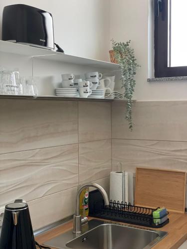a kitchen sink with plates and cups on a shelf at Morpheus apartmani in Sremska Mitrovica