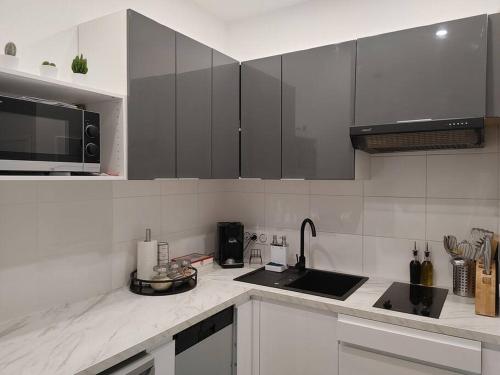 a kitchen with black and white cabinets and a sink at Cocon lumineux avec parking et sauna Paris direct in Asnières-sur-Seine