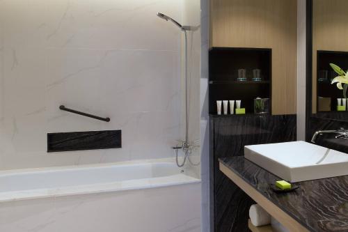 a bathroom with a sink and a bath tub and a white sink at Le Meridien Kota Kinabalu in Kota Kinabalu