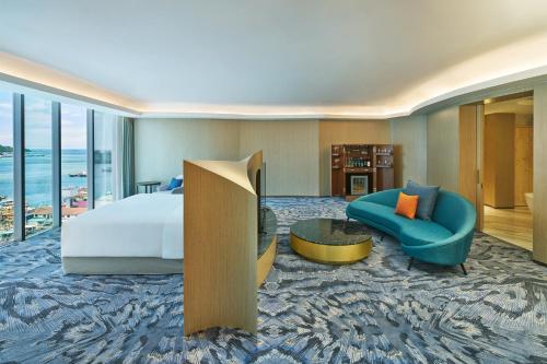 a hotel room with a bed and a couch and a chair at Le Meridien Kota Kinabalu in Kota Kinabalu