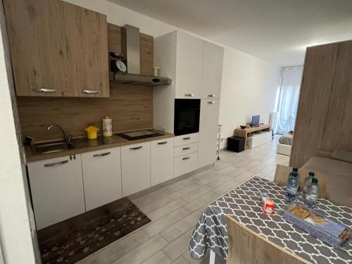 una cucina con armadi bianchi e un tavolo di Einaudi Apartment a Cologno Monzese