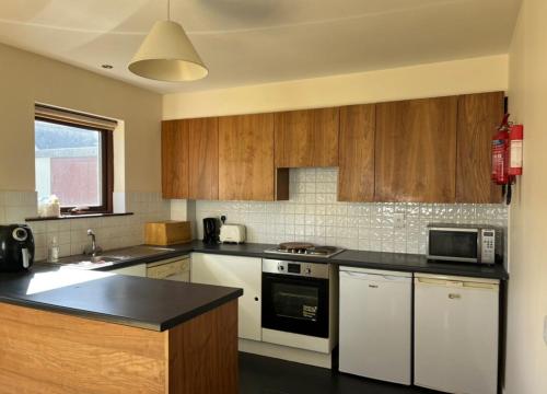 una cocina con electrodomésticos blancos y armarios de madera en No. 6 Corran Meabh en Lahinch