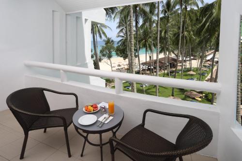 uma varanda com duas cadeiras e uma mesa com comida em Le Meridien Phuket Beach Resort - em Praia de Karon