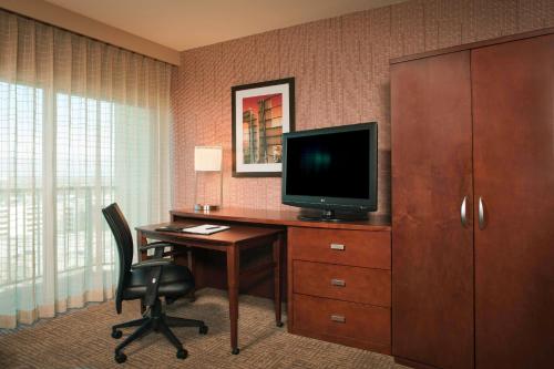 a hotel room with a desk with a tv and a chair at Courtyard Los Angeles Sherman Oaks in Sherman Oaks