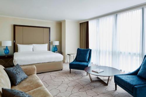 a hotel room with a bed and a couch and chairs at London Marriott Hotel Canary Wharf in London