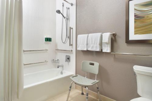 a bathroom with a white tub and a chair in it at Courtyard by Marriott Nashville Airport in Nashville