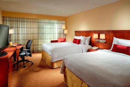 a hotel room with two beds and a desk and a television at Courtyard by Marriott Columbus in Columbus