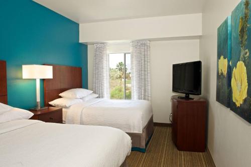 Habitación de hotel con 2 camas y TV de pantalla plana. en Residence Inn Palm Desert en Palm Desert