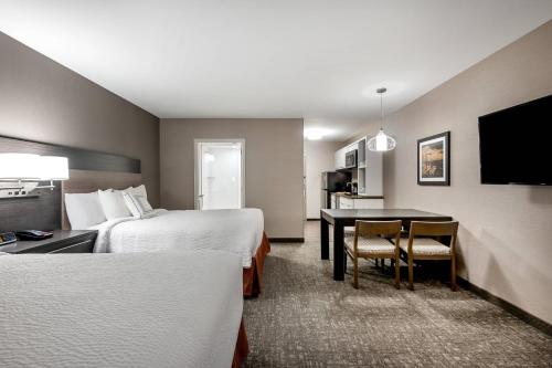 a hotel room with two beds and a desk with a table at TownePlace Suites by Marriott Whitefish in Whitefish