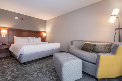 um quarto de hotel com uma cama e uma cadeira em Courtyard by Marriott Charlotte Lake Norman em Huntersville