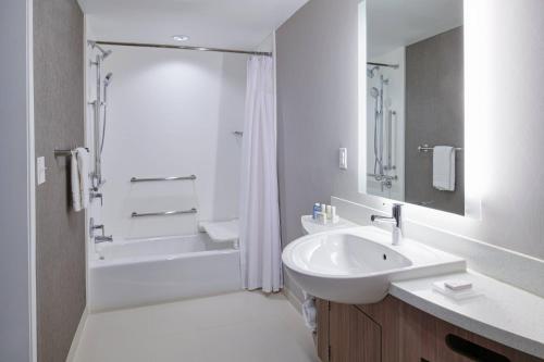 a white bathroom with a sink and a shower at SpringHill Suites by Marriott Detroit Wixom in Wixom