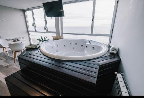 bañera grande en una habitación con ventanas en Loft 7 piso frente al mar para 2 personas en Monte Hermoso