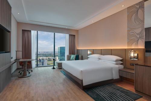 a bedroom with a large white bed and a large window at Courtyard by Marriott Setia Alam in Setia Alam