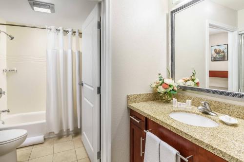 a bathroom with a sink and a toilet and a mirror at Residence Inn Burlington Colchester in Burlington