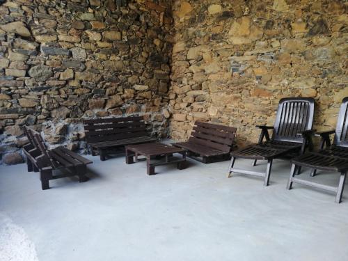 a group of wooden benches sitting in front of a stone wall at Casa Carlán in Melide