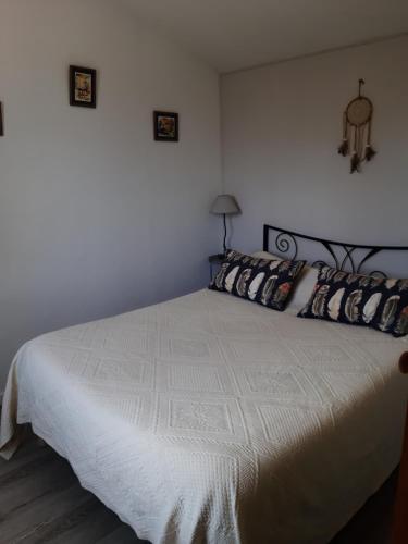 - une chambre avec un grand lit blanc et des oreillers dans l'établissement L'Oustalet, à Carbonne