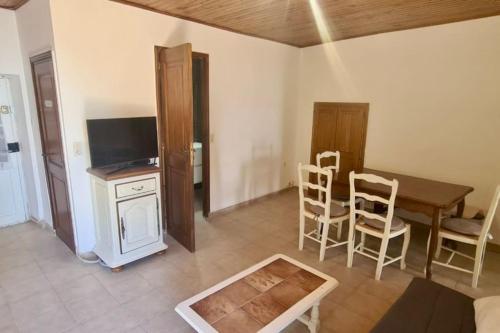 Village de Pozzo appart. 4 pers. في Brando: غرفة معيشة مع طاولة وكراسي وتلفزيون