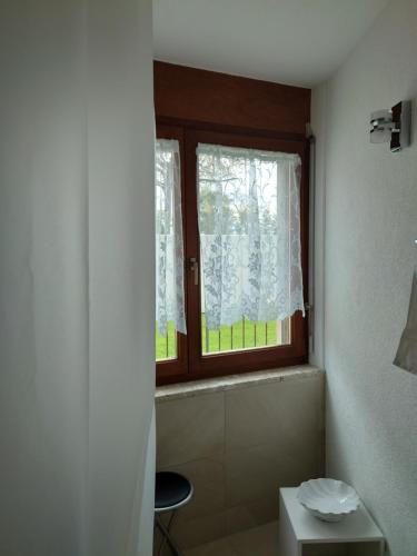 a bathroom with a window and a toilet and a stool at Maison Champperbou in Haut-Vully