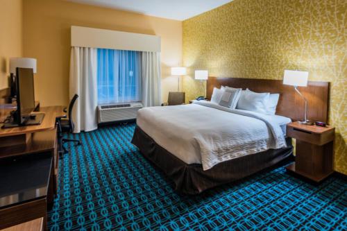a hotel room with a bed and a desk and a television at Fairfield Inn & Suites by Marriott Atlanta Fairburn in Fairburn