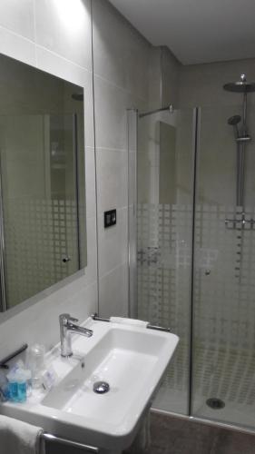 a bathroom with a sink and a shower with a mirror at Apartamentos Las Palmeras in Palma del Río