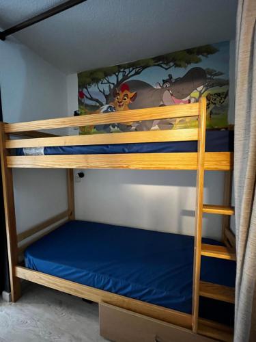 a bunk bedded room with two bunk beds with blue sheets at Ski Piau engaly 50 m des pistes de ski et du cœur de station in Aragnouet