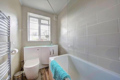 a white bathroom with a tub and a toilet at 2 bed flat - SW London with parking in Teddington