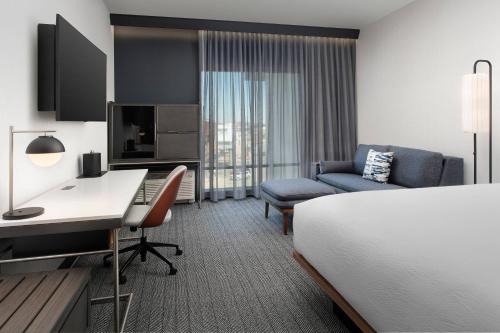 a hotel room with a bed and a desk and a couch at Courtyard by Marriott Indianapolis Plainfield in Plainfield