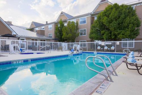 a swimming pool with chairs in front of a building at Residence Inn by Marriott Albuquerque North in Albuquerque
