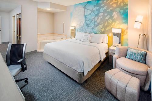 a hotel room with a bed and a chair at Courtyard by Marriott West Palm Beach Airport in West Palm Beach