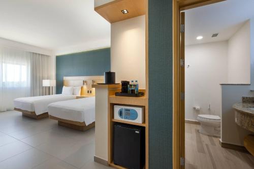 a hotel room with a bed and a bathroom at Courtyard by Marriott Cancun Airport in Cancún